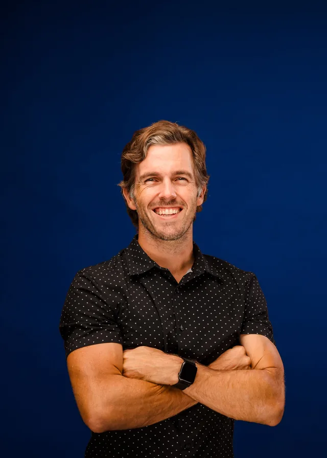 Bud Johnson with arms crossed against a blue backdrop