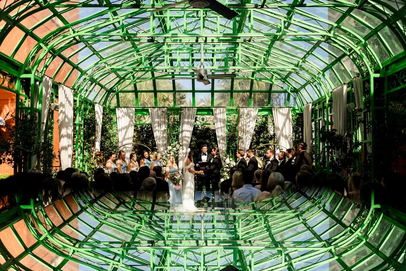 Glass courtyard glowing green at night with a couple reflected in the floor