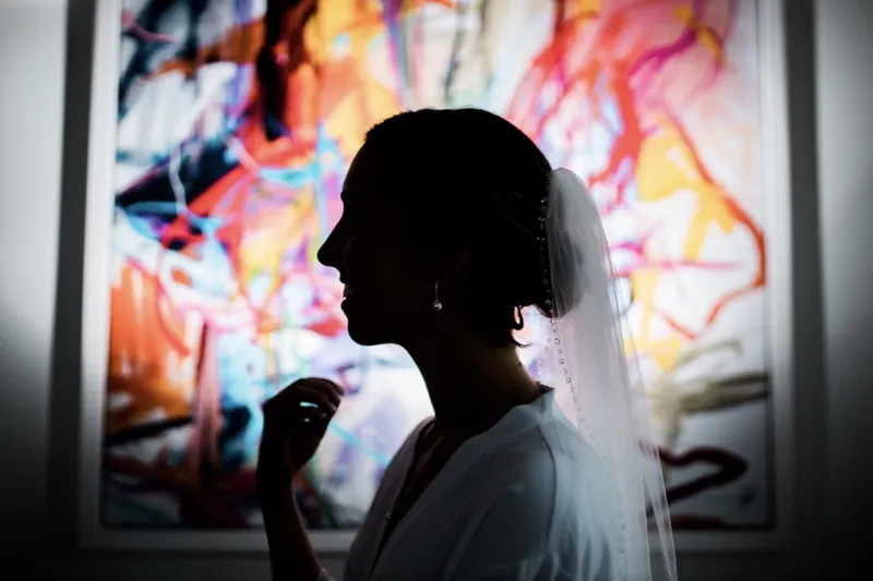 Bride silhouetted against a bright abstract painting