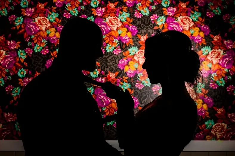 Couple silhouetted against a wall of flowers