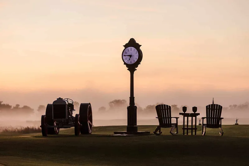 A town clock and an old tractor in fog at first light